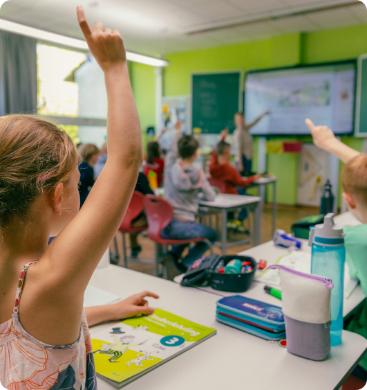 Mädchen hebt die Hand in einem modernen Klassenzimmer mit digitaler Tafel.